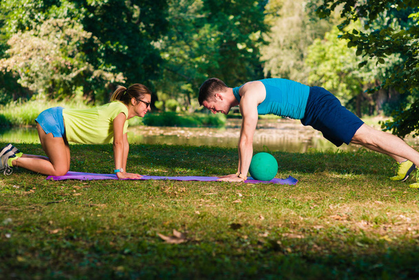 Couple athlétique entraînement push ups sur l'herbe dans le parc
 - Photo, image