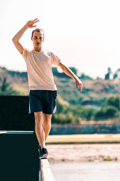 Sportive man exercising while walk on edge outdoors - Photo, image