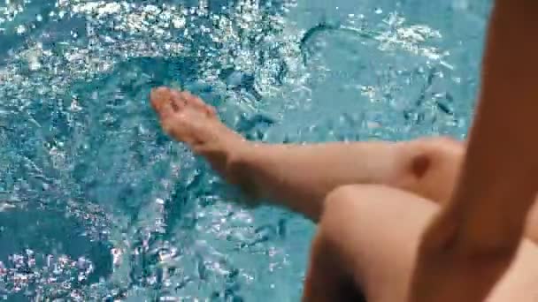 Barefoot female sunbathing playing feet in pure water at outdoor swimming pool slow motion - Footage, Video