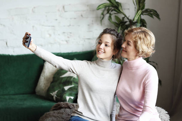 beautiful mature mother and her daughter making a selfie using smart phone and smiling, home and happy. Lifestyle. - Φωτογραφία, εικόνα