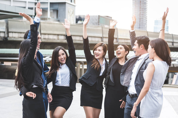 Портрет успешной группы деловых людей на открытом воздухе города. Счастливые бизнесмены и деловые женщины поднимают руку в знак удовлетворения. Успешная группа людей, улыбающихся после достижения
 - Фото, изображение
