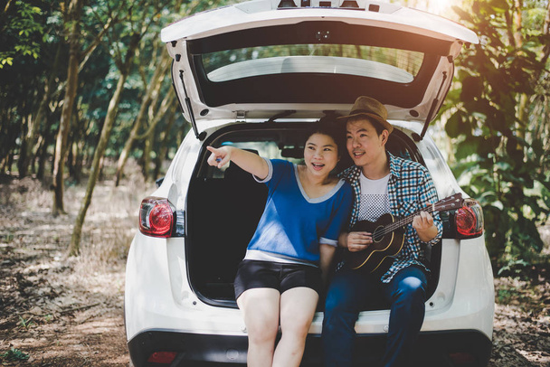 asiatisches Paar, das mit dem Auto in den Wald fährt, Musikerliebhaber. Abenteuer und Outdoor-Konzept. Thema Natur und Lifestyle. Roadtrip-Thema. - Foto, Bild