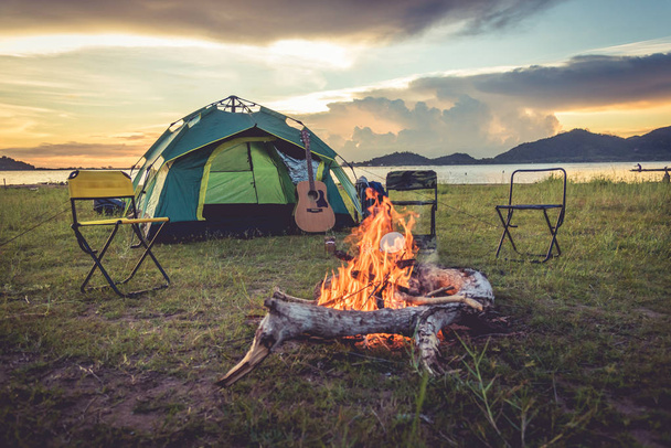 Kemping sátor, a tábortűz, a zöld mező, rét, és a hegyi tó háttérben. Piknik és utazási fogalom. Természet téma. - Fotó, kép