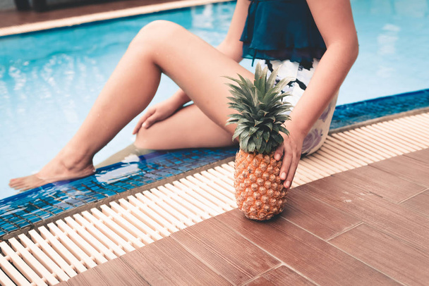 Close-up portrait of woman holding pineapple beside swimming pool., Summer holiday concept. - Photo, Image