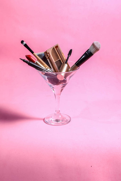 makeup tools in Martini glass on pink background - Photo, Image
