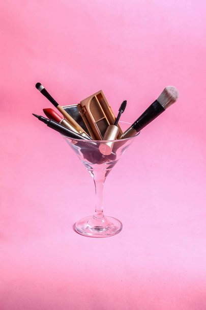 makeup tools in Martini glass on pink background - Fotó, kép