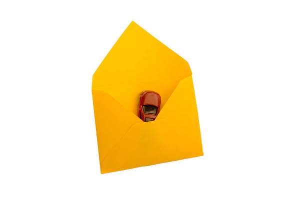 Маленькая красная машина в желтом конверте - Фото, изображение