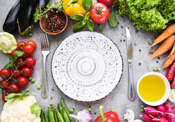 Empty plate and fresh vegetables on a concrete background - Photo, Image