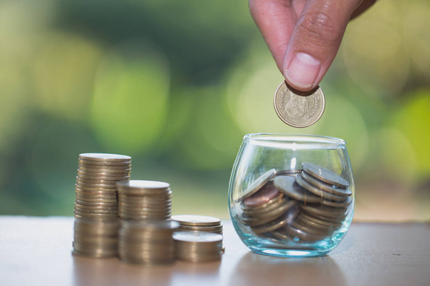 La mano de la mujer poniendo moneda en un vaso de botella para ahorrar dinero, ahorrando concepto de dinero
 - Foto, imagen