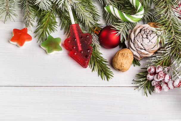 Різдвяні цукерки та ялинкові гілки на світлому дерев'яному фоні
. - Фото, зображення