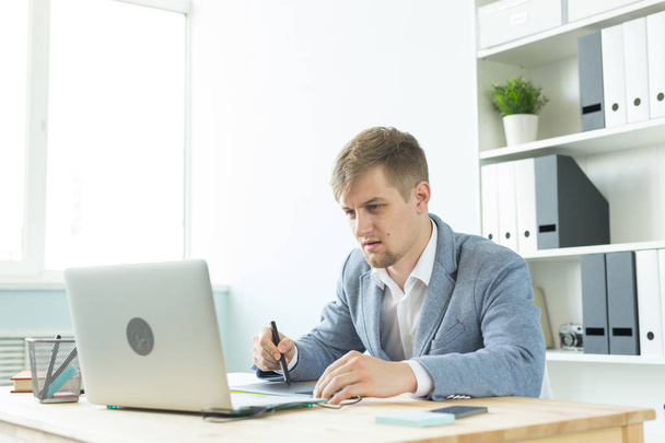 Suunnittelija, taiteilija ja web design käsite - Muotokuva nuori mies käyttää digitaalista kynä tabletti ja kannettava tietokone toimistossa
 - Valokuva, kuva