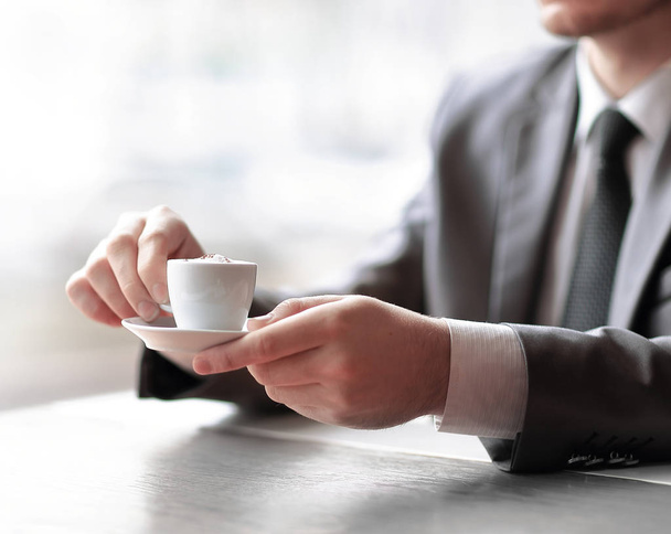 close up.businessman holding a Cup of coffee sitting at his Desk - 写真・画像