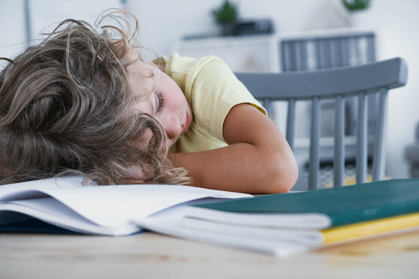 Zbliżenie: zmęczony dziecko śpi z głową, położył na stół z książki. - Zdjęcie, obraz