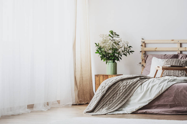Trendy bedroom interior with comfortable bed with dirty pink bedding and beige warm blanket, real photo with copy space - Valokuva, kuva