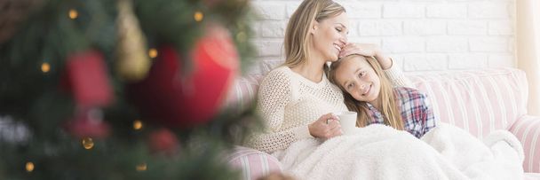 Girl sitting with her mother on a couch - Foto, Bild