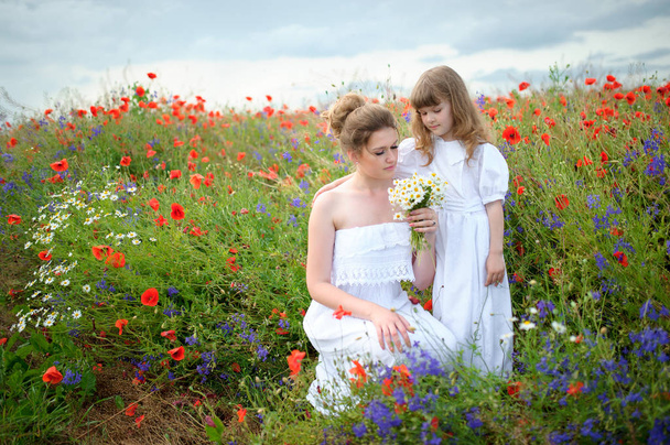 mutlu anne ve kızı yabani çiçek çiçeklenme meadows arasında sarılma - Fotoğraf, Görsel