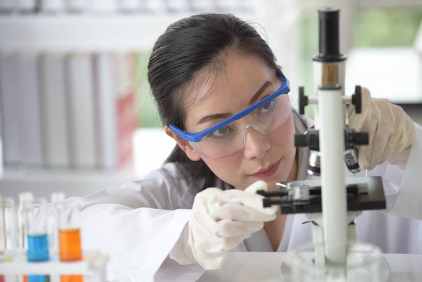 若い女性の科学者実験室で科学と実験しています。アジアの科学者が研究室で試験管を保持 - 写真・画像