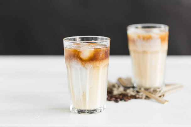 Caffè freddo in un bicchiere con crema sopra e chicchi di caffè sul tavolo
 - Foto, immagini