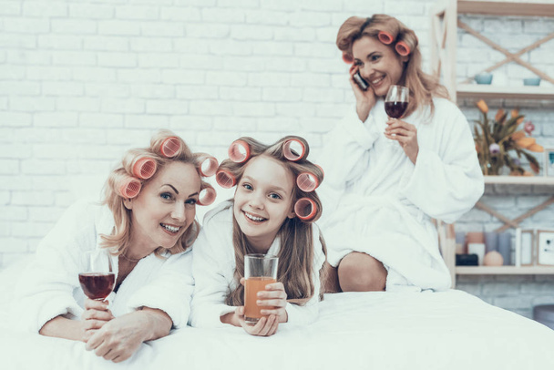 Women in White Bathrobes with Drink in Glasses. Have Fun at Home. Happy Family. Mother with Daughter. Smiling Women. Lying on Sofa. Have Fun Indoor. Family after Bath. Women's Beauty Concept. - Valokuva, kuva