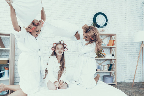 Smiling Women in White Bathrobes Have Fun at Home. Happy Family. Mother with Daughter. Smiling Women. Smiling Grandmother. Have Fun Indoor. White Sofa. Family after Bath. Pillow Fight. - Foto, Bild