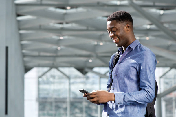 Портрет счастливого молодого чернокожего бизнесмена, смотрящего на мобильный телефон
  - Фото, изображение