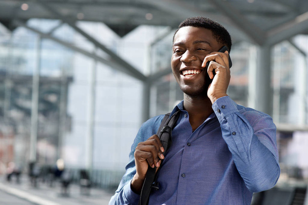 Gros plan portrait d'un homme d'affaires afro-américain souriant parlant sur son portable à la station
 - Photo, image