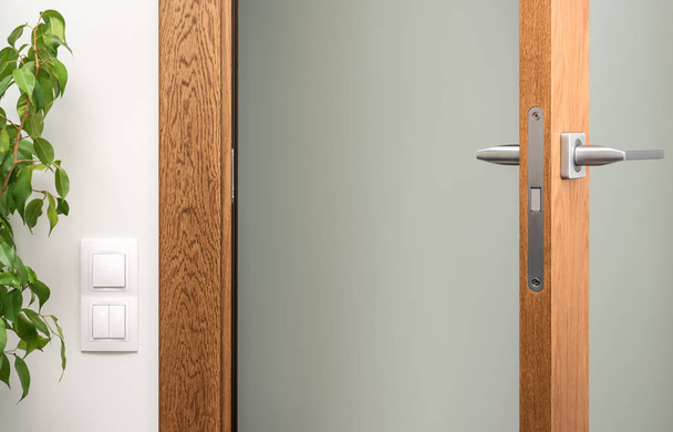 Open interior door. Close-up of door handle and lock. White switches on the wall - Fotó, kép