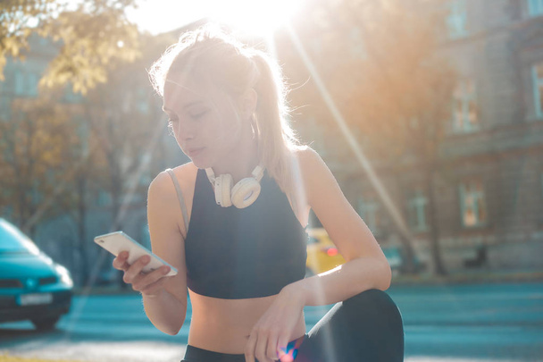 Young pretty girl looking at her phone while working out - 写真・画像