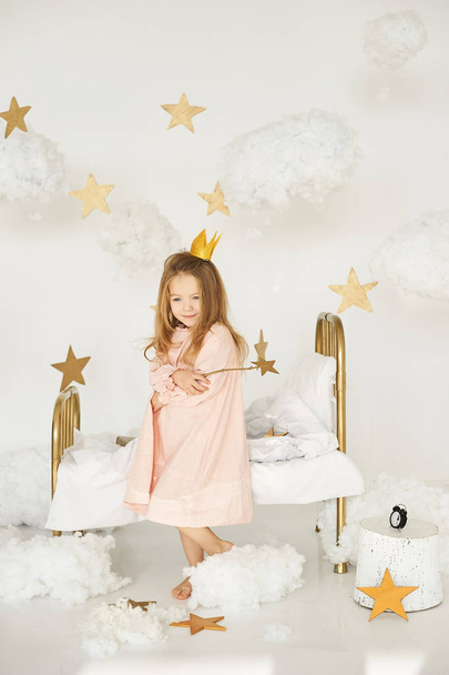 Little princess with a magic wand on  bed in a cloud on a white background - Zdjęcie, obraz