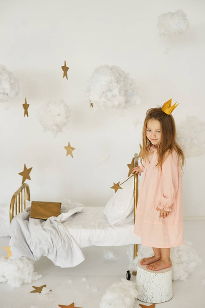 Little princess with a magic wand on  bed in a cloud on a white background - Фото, зображення