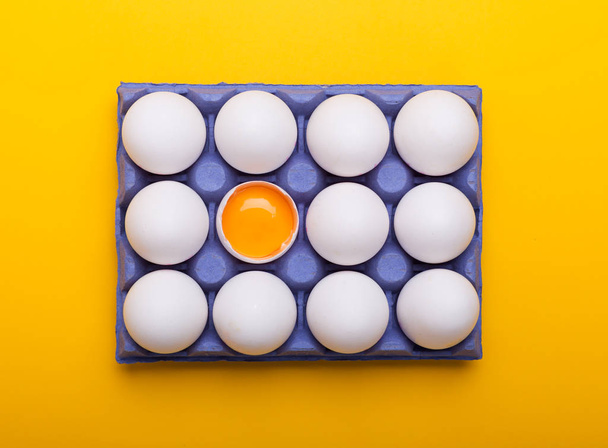 White eggs and egg yolk in the blue box on the yellow background - Foto, Imagen