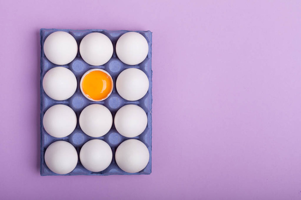 White eggs and egg yolk in the blue box on the purple background - Φωτογραφία, εικόνα