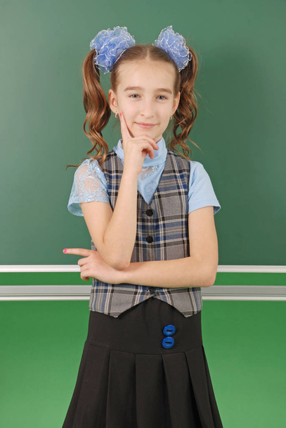 Χαριτωμένο κορίτσι μαθήτρια κοντά σε μαυροπίνακα η έννοια της εκπαίδευσης και της σχολικής ζωής - Φωτογραφία, εικόνα