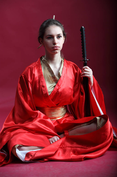Beautiful brunette girl in a japanese kimono with a katana - Foto, afbeelding