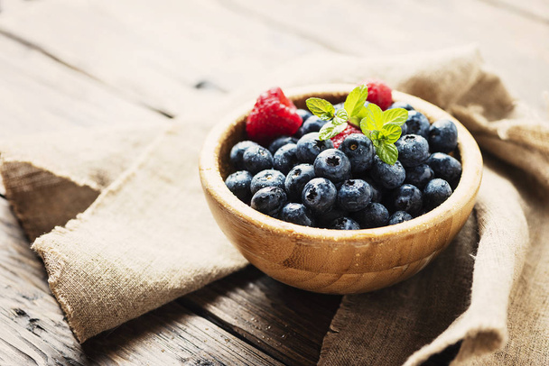 Fresh blueberries with mint on wooden table - Foto, imagen