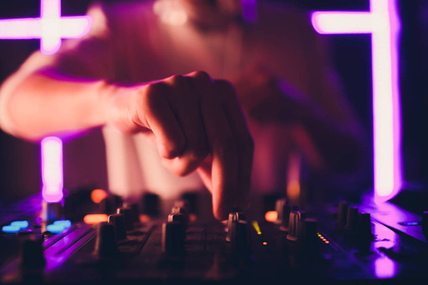 DJ playing music at mixer on colorful blurred background. - Photo, Image