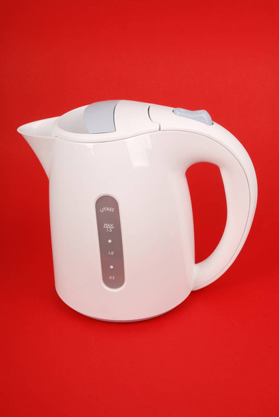 Белый электрический чайник изолирован на красном фоне
 - Фото, изображение