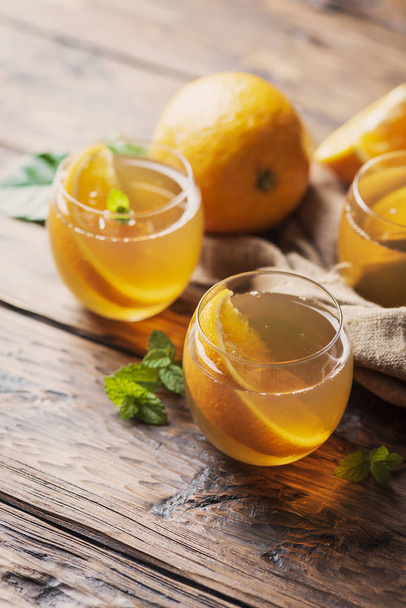 Cold tea with orange and mint on wooden table - Foto, imagen