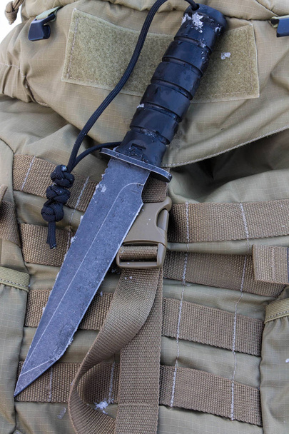 Couteau de combat sur le dos militaire de sable. Noir irom
. - Photo, image
