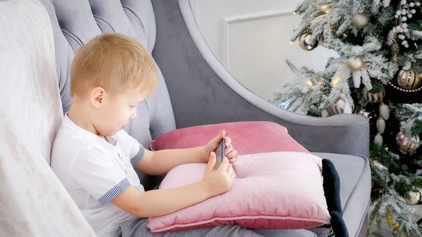 Chłopiec gry smartphone na kanapie - Zdjęcie, obraz