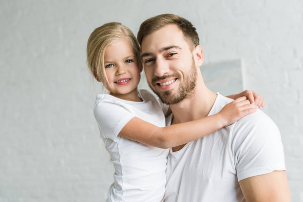 happy father and cute little daughter hugging and smiling at camera - Фото, зображення