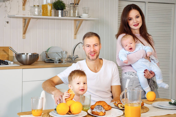 赤ちゃんと一緒に朝食のための台所で少年の両親 - 写真・画像