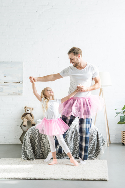 Šťastný otec a dcera v růžové tutu sukně, drželi se za ruce a tančí spolu - Fotografie, Obrázek