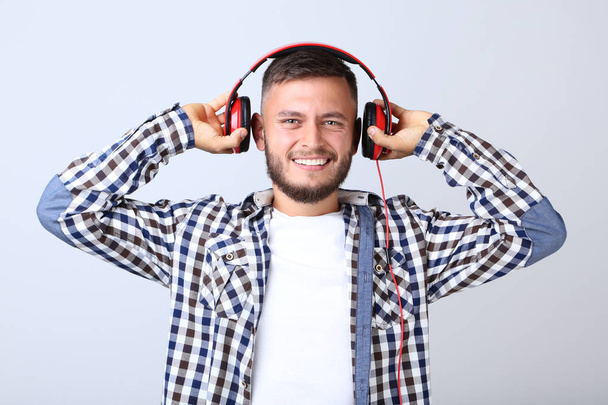 Young man with red headphones on grey background - Foto, imagen