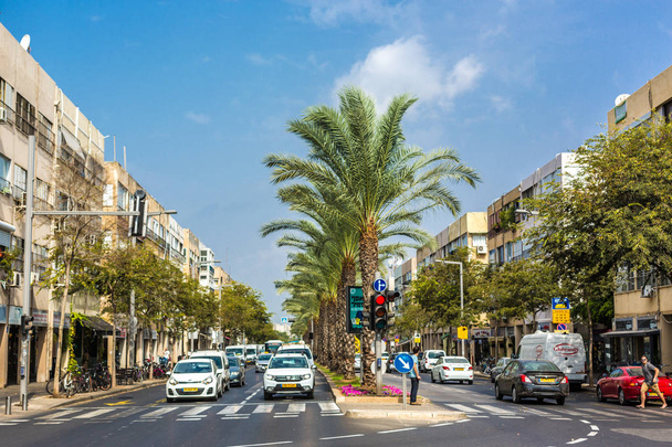 Tel Aviv, Israel - Oct 26th 2018 - A busy road with cars and buildings around and palm trees in a blue sky day in Tel Aviv, Israel - Photo, Image
