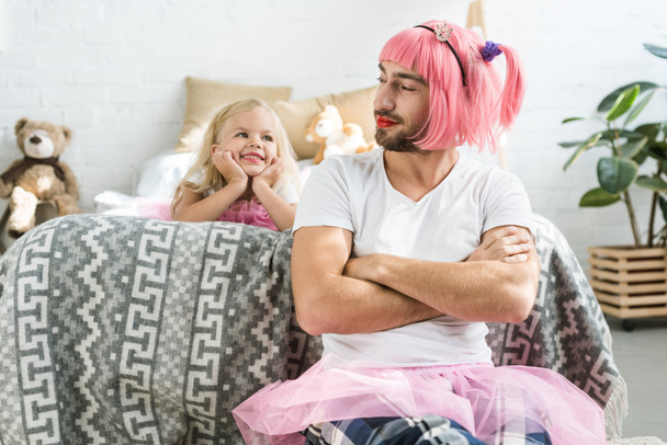 adorable feliz hija mirando sonriente padre en rosa peluca y tutú falda
   - Foto, imagen