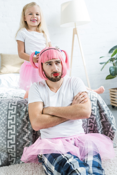 adorable happy daughter playing with father in pink wig and tutu skirt  - Foto, Bild