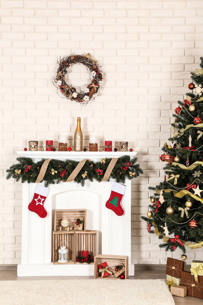 Decorated fireplace near christmas tree on brick wall background - 写真・画像
