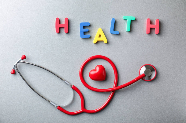 Word HEALTH made of colorful letters with stethoscope on grey background - Foto, Bild