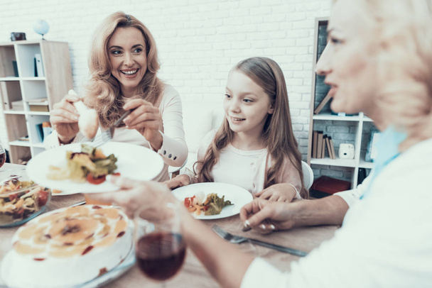 Happy Sitting Family Celebrating Birthday at Home. Cake on Table. Happy Family. Mother with Daughter. Smiling Women. Smiling Grandmother. Celebration Concept. Glass of Wine. Fruits on Plate. - 写真・画像